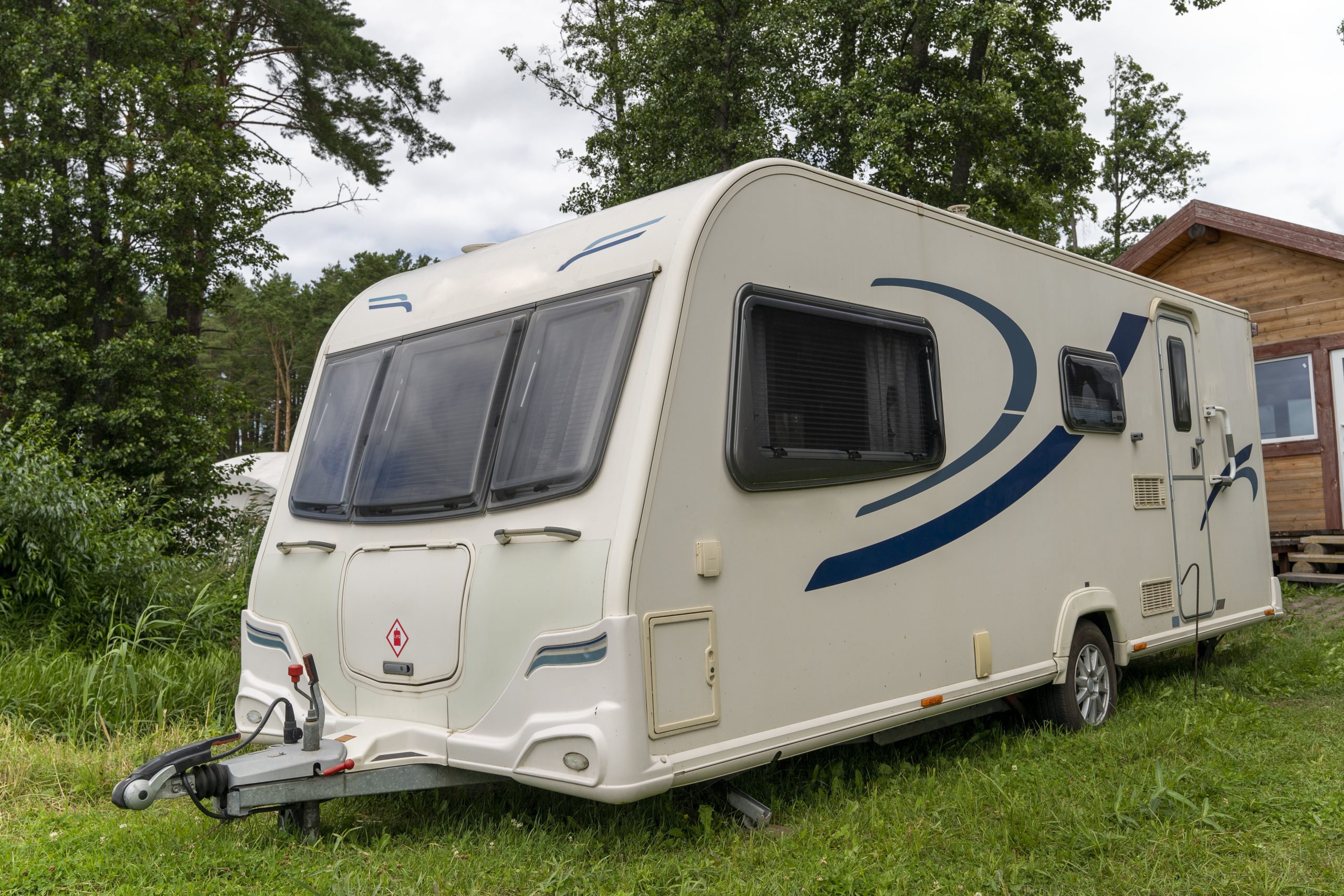 A Camper trailer for traveling standing on the shore of the lake in summer. The concept of car travel with the whole family. Vacation